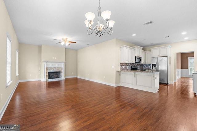 unfurnished living room featuring dark hardwood / wood-style floors, ceiling fan with notable chandelier, and a fireplace