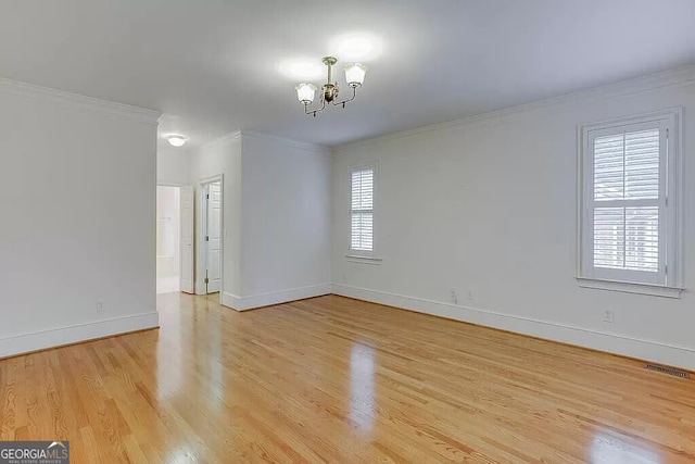 spare room featuring crown molding, light wood-type flooring, and an inviting chandelier