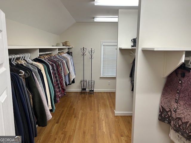 walk in closet with vaulted ceiling and light wood-type flooring