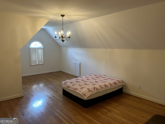 unfurnished bedroom with an inviting chandelier, wood-type flooring, and vaulted ceiling