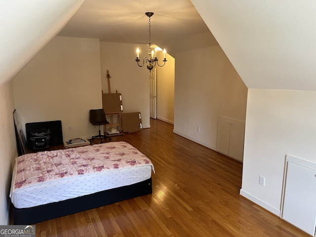 bedroom with an inviting chandelier, lofted ceiling, and hardwood / wood-style floors