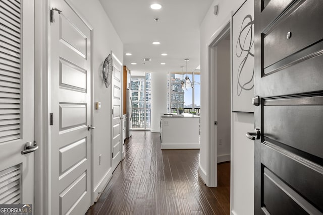 corridor with dark hardwood / wood-style flooring and an inviting chandelier