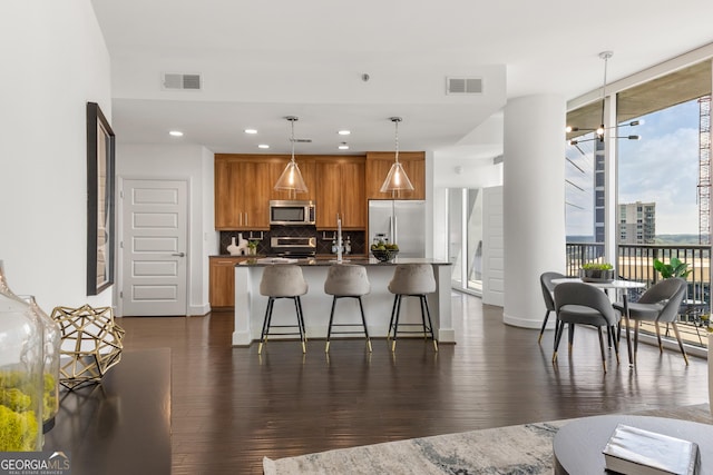 kitchen featuring a breakfast bar, backsplash, expansive windows, appliances with stainless steel finishes, and decorative light fixtures