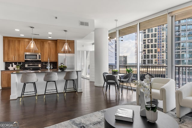 kitchen with decorative backsplash, expansive windows, stainless steel appliances, dark wood-type flooring, and decorative light fixtures