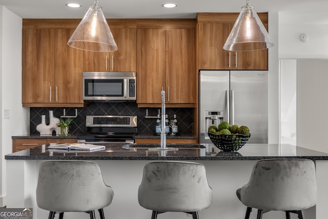 kitchen with backsplash, stainless steel appliances, a center island with sink, and sink