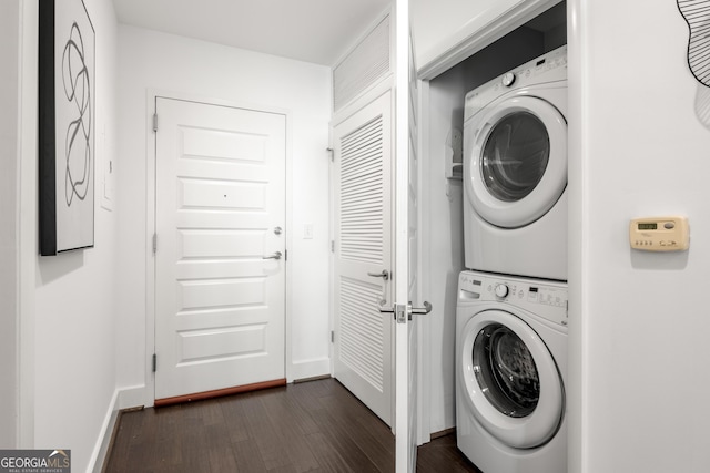 laundry area featuring stacked washer / dryer and dark wood-type flooring