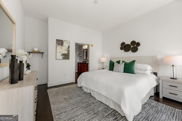 bedroom with ensuite bathroom and dark wood-type flooring