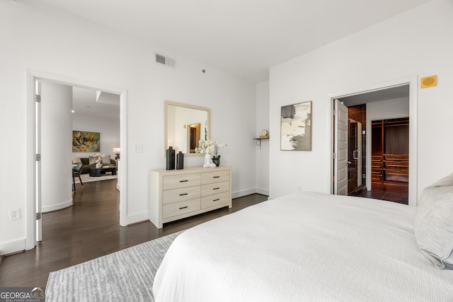 bedroom featuring a walk in closet, a closet, and dark wood-type flooring