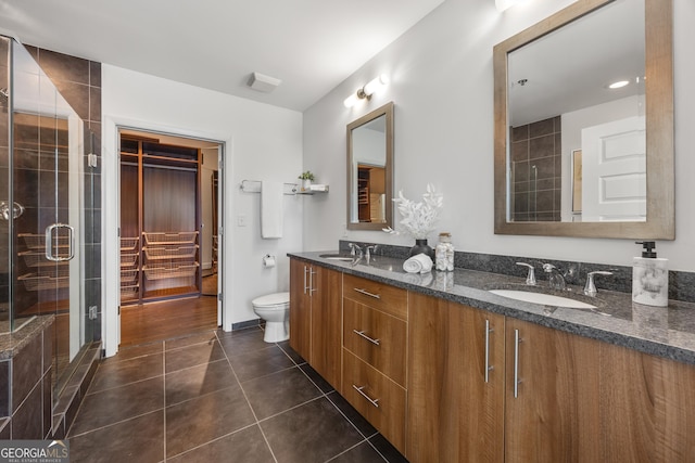 bathroom with toilet, vanity, tile patterned floors, and a shower with shower door