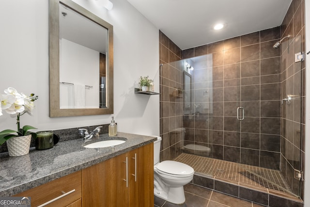 bathroom featuring tile patterned floors, vanity, a shower with shower door, and toilet