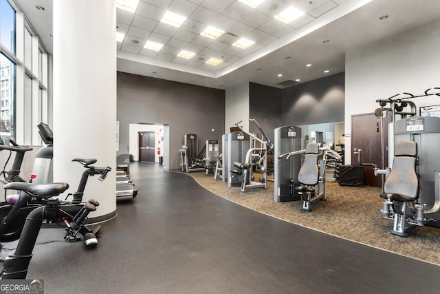 gym featuring a paneled ceiling and a towering ceiling