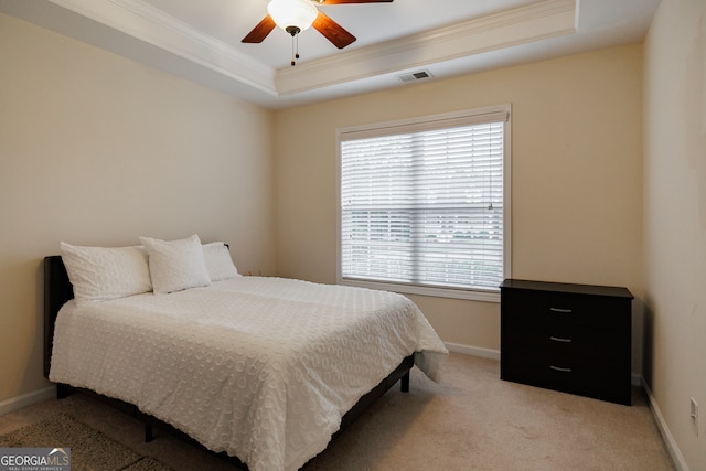 bedroom with light colored carpet, ceiling fan, crown molding, and a tray ceiling