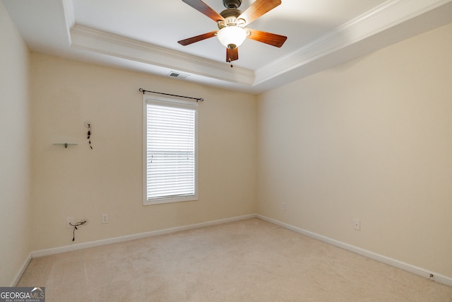 empty room with ornamental molding, light colored carpet, ceiling fan, and a tray ceiling