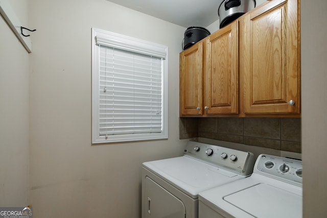 clothes washing area featuring washing machine and dryer and cabinets