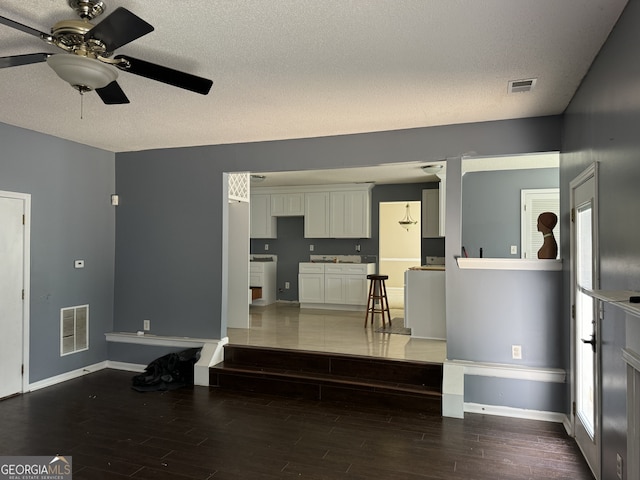 living room featuring ceiling fan, hardwood / wood-style floors, and a textured ceiling