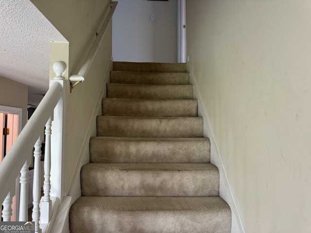 stairway with a textured ceiling