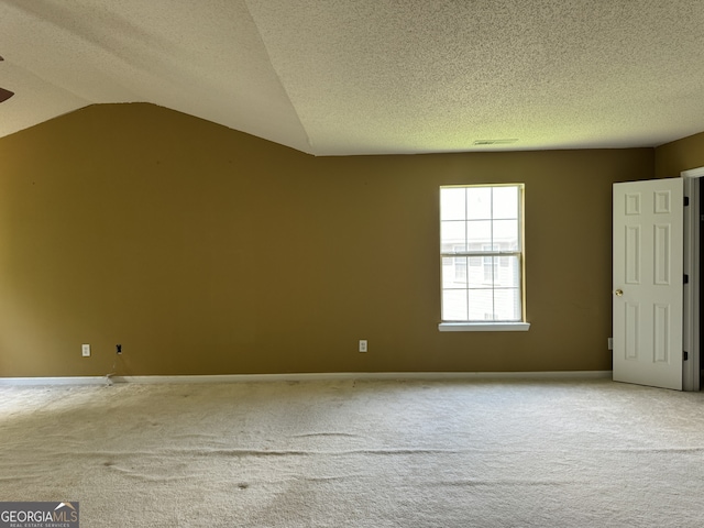 empty room with vaulted ceiling, a textured ceiling, and carpet