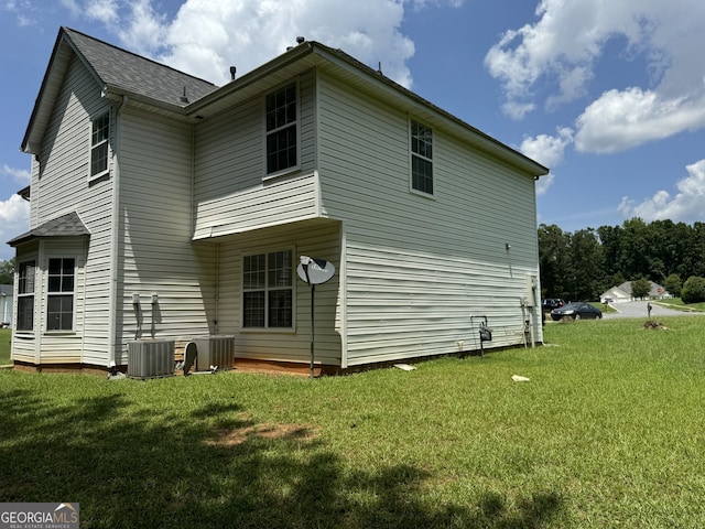 rear view of property featuring a yard and cooling unit