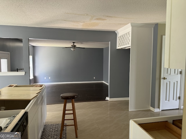 kitchen featuring light tile patterned flooring, ceiling fan, a textured ceiling, and white cabinets