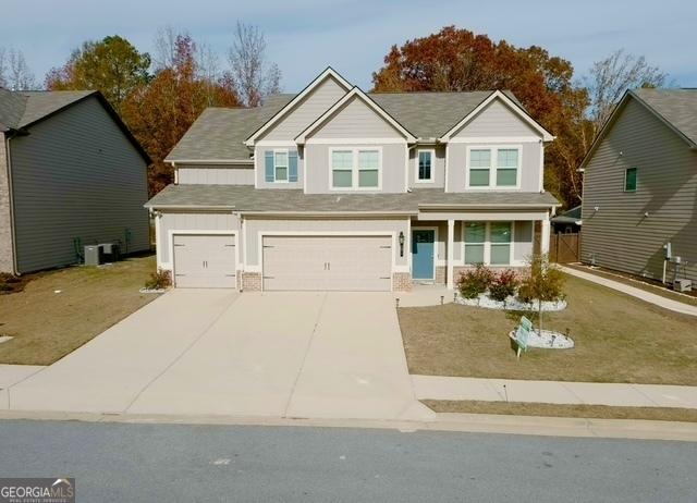 view of front of house with a garage, cooling unit, and a front lawn