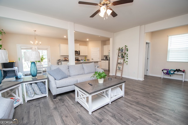 living room with ceiling fan with notable chandelier and hardwood / wood-style flooring