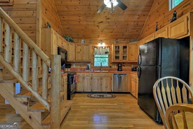 kitchen with wooden walls, sink, light hardwood / wood-style flooring, and black appliances