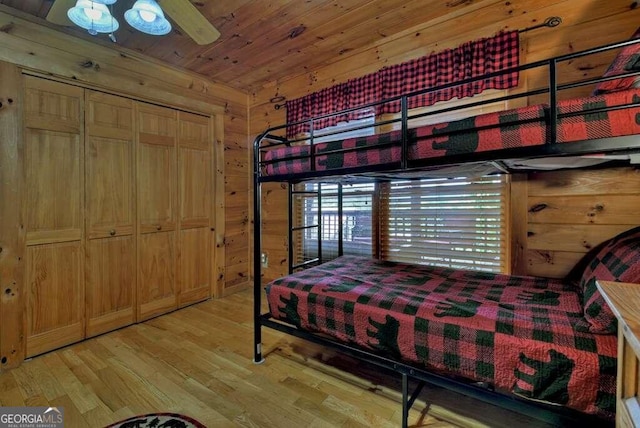 bedroom with wood walls, light wood-type flooring, ceiling fan, and wooden ceiling