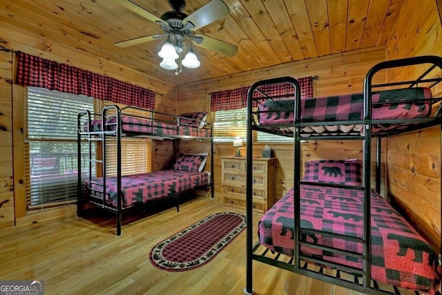 bedroom with ceiling fan, wooden walls, light wood-type flooring, and wooden ceiling