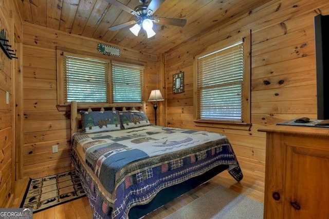 bedroom featuring wood ceiling, ceiling fan, wood walls, and light hardwood / wood-style flooring