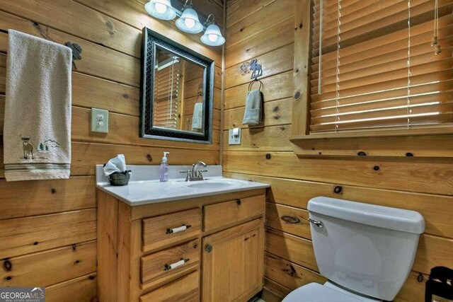 bathroom with toilet, wooden walls, and vanity