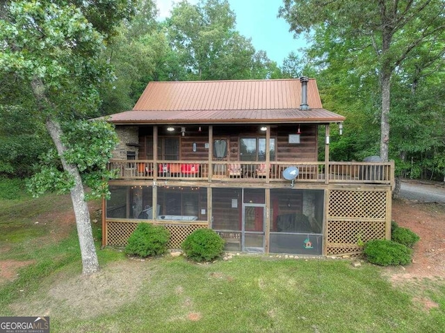 rear view of property featuring a sunroom and a lawn