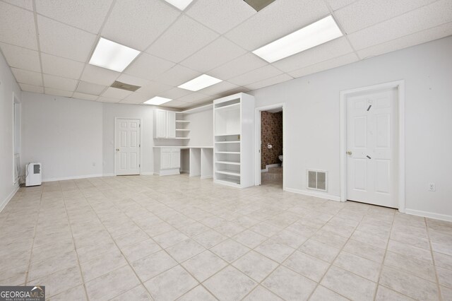 basement with a paneled ceiling and light tile patterned floors