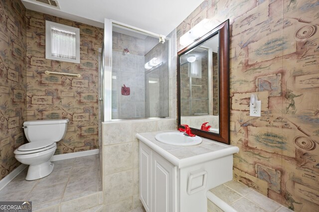 bathroom featuring vanity, tile patterned floors, toilet, and tile walls