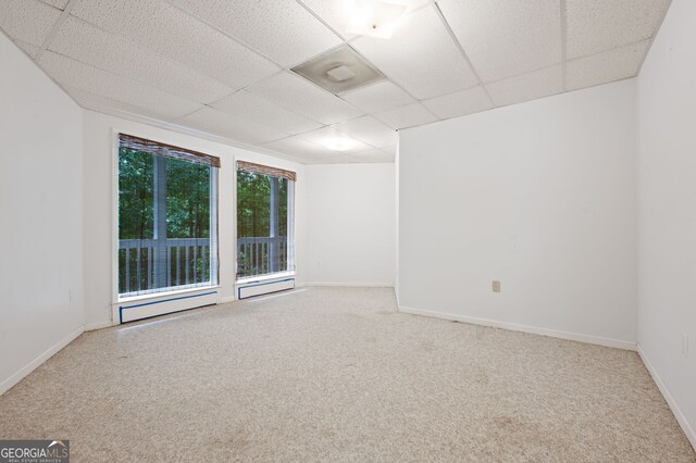 carpeted empty room featuring a drop ceiling