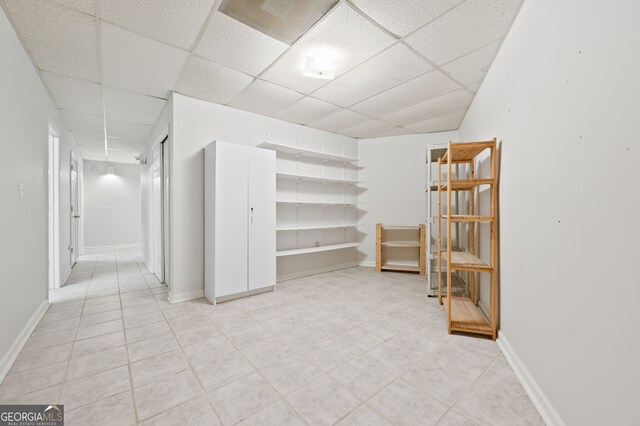 basement featuring light tile patterned floors and a paneled ceiling