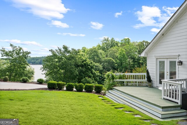 view of yard with french doors and a deck with water view