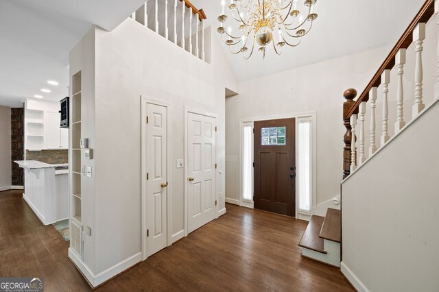 foyer entrance with high vaulted ceiling, dark hardwood / wood-style floors, and a chandelier