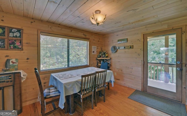 dining space featuring wooden walls, light wood-type flooring, and wood ceiling