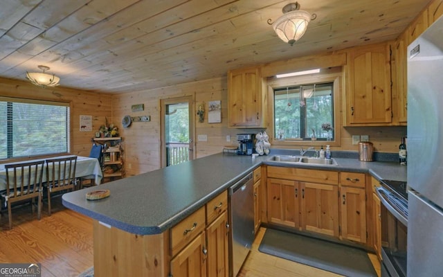 kitchen featuring range, light hardwood / wood-style floors, wooden walls, and plenty of natural light