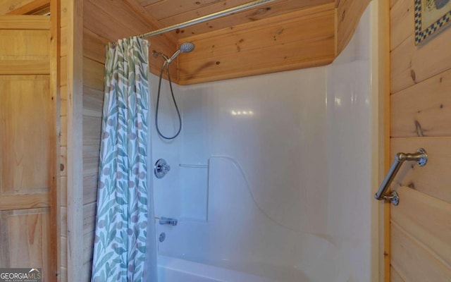 bathroom with wooden walls and shower / tub combo with curtain