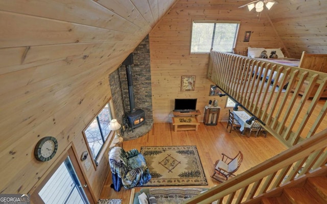 living room featuring wood-type flooring, wood walls, a wood stove, wooden ceiling, and high vaulted ceiling