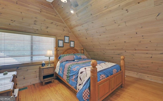 bedroom with light hardwood / wood-style flooring, lofted ceiling, ceiling fan, wood ceiling, and wood walls