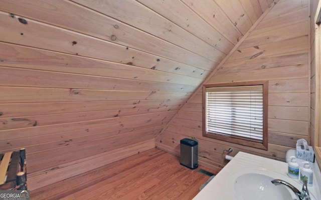 bathroom featuring wooden walls, wood ceiling, hardwood / wood-style floors, and vaulted ceiling