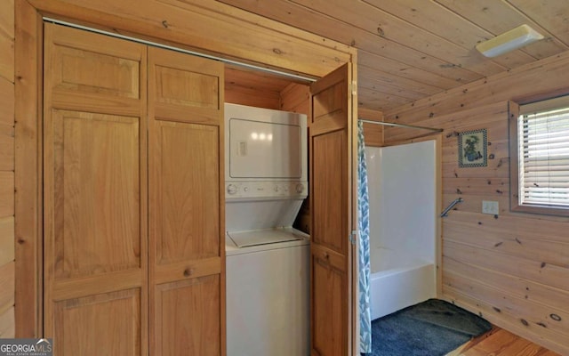 clothes washing area with stacked washer / dryer, hardwood / wood-style floors, wooden walls, and wood ceiling