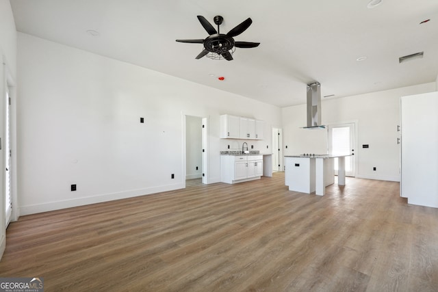 unfurnished living room featuring light hardwood / wood-style floors, sink, and ceiling fan