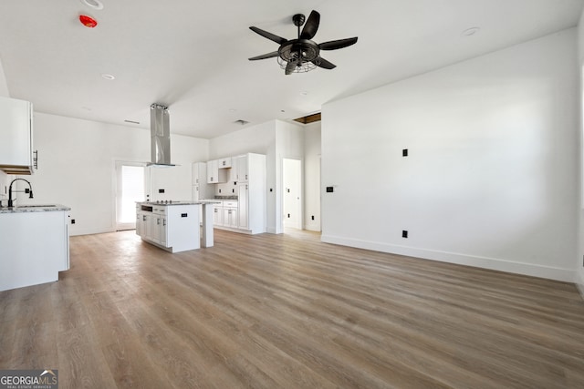 unfurnished living room with sink, light wood-type flooring, and ceiling fan