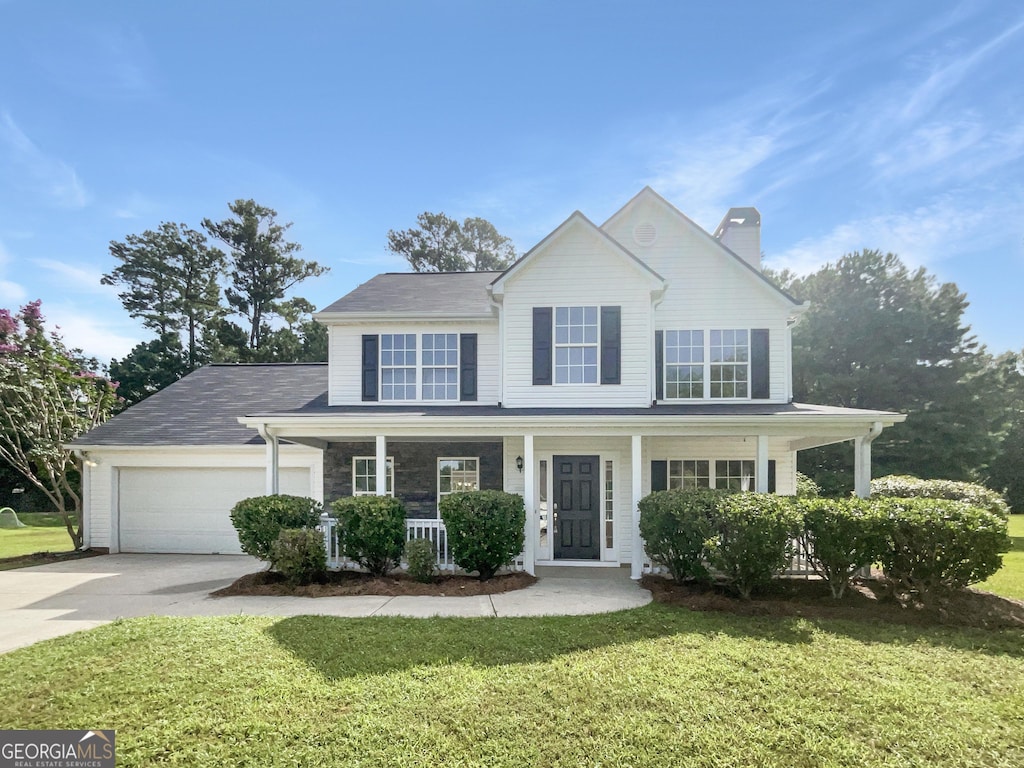 view of front of home featuring a garage, a front yard, and a porch