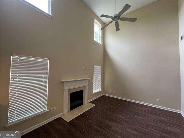 unfurnished living room with a premium fireplace, ceiling fan, hardwood / wood-style flooring, and a high ceiling