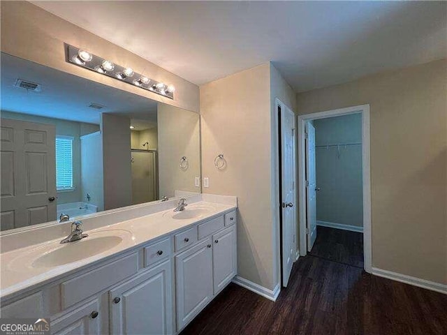 bathroom with double vanity, separate shower and tub, and hardwood / wood-style floors