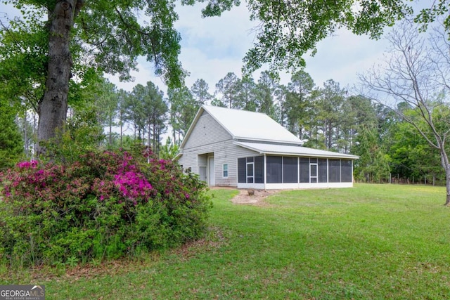 view of home's exterior with a sunroom and a yard